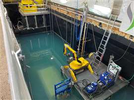 A remote controlled demolition robot suspended above the water-flooded reactor vessel.