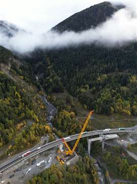 A crane and machinery working on a motorway in the mountains