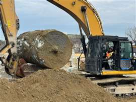 An excavator moving a concrete caisson