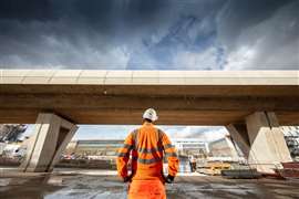 A construction worker stands with his back to the camera, hands on hips, looking at a completed section of the Curzon No 3 viaduct on the HS2 high-speed railway in