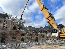 A long reach excavator equipped with a grapple pulls down damage scaffolding