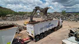 An excavator loads a truck with scrap metal C&D waste