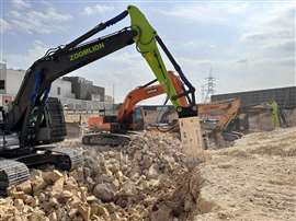 Four excavators with hydraulic attachments in action