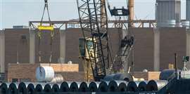 A crane moves a steel coil (Image: Adobe Stock)