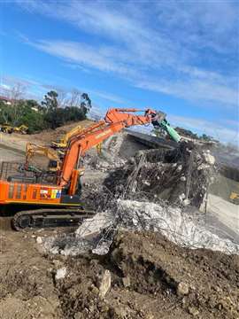 A Hitachi 470LCR-5G with the OilQuick system demolishing a bridge structure under shutdown conditions