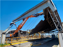 A demolition excavator tears through the metal roofing of the Bunge Bahía Blanca plant in Argentina