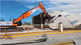 A demolition excavator tears through the metal roofing of the Bunge Bahía Blanca plant in Argentina