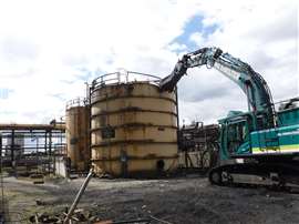 A demolition excavator dismantling the a Benzol tank onsite