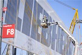 Workers attach decorative elements to the outer facade of the Liebherr stand